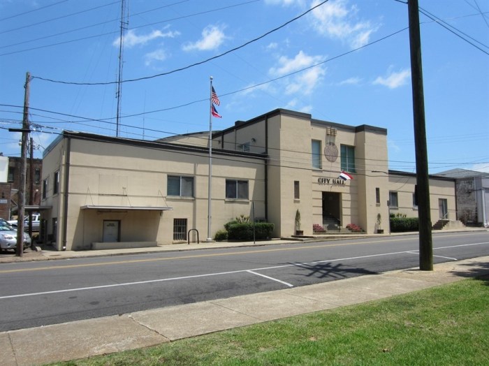 Starkville City Hall, Starkville, Oktibbeha County. Starkville’s Art Moderne-style former armory and City Hall, built 1940-41, has a two-story central mass with one-story wings to each side. is historically significant because of its association with the military, WPA, and Starkville local government. The building is one of seven armories built in Mississippi built on a Moderne-style prototype design prepared for the Mississippi National Guard by the Jackson firm of Overstreet and Town. N.W. Overstreet was the dean of the architectural profession in Mississippi and A. Hays Town was one of the state’s most gifted designers during the 1930s and was particularly adept in the Modern style. Overstreet and Town were also pioneers of poured-in-place concrete construction in the state in the 1930s. In “Design for Concrete Armories-Mississippi,” Overstreet described the advantages of the design: “in many small [Mississippi] towns the armory is the only community center, the only theatre, gymnasium or public place of assembly.” For this reason, the prototype design included a stage with a proscenium in the drill hall.